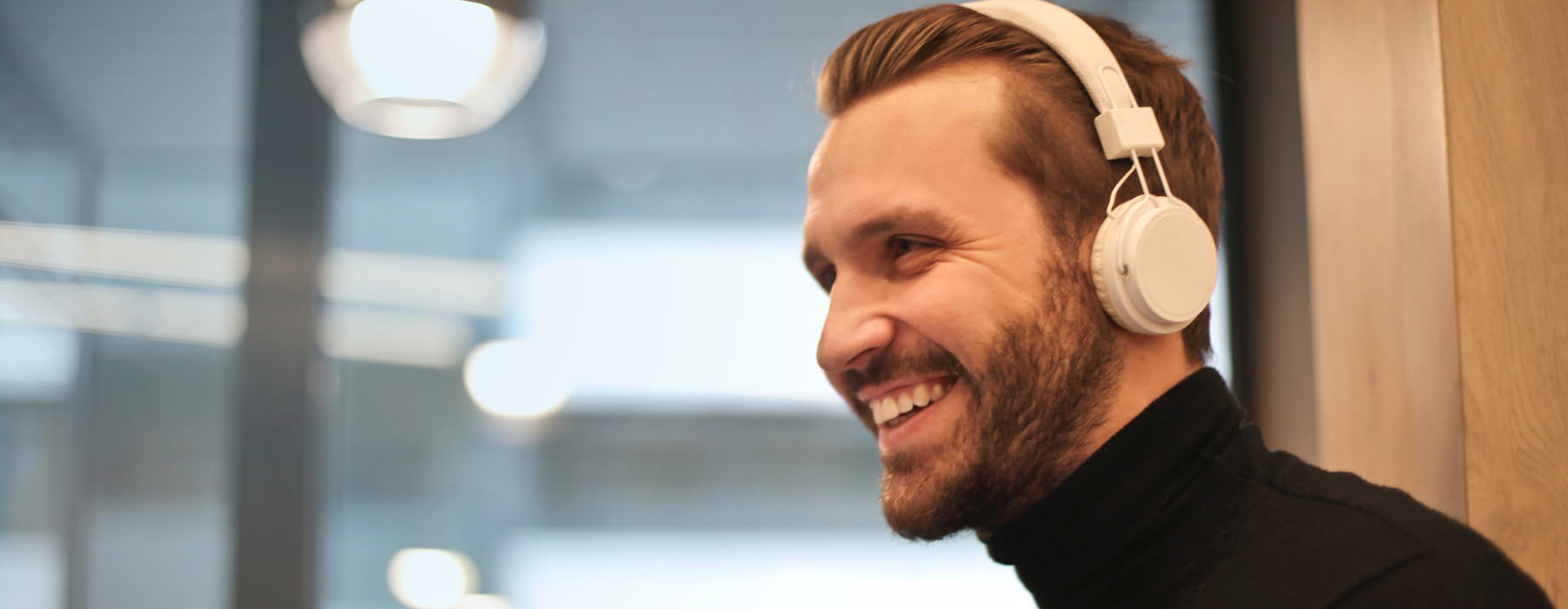 smiling, bearded man with headphones on